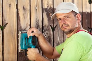 Jerry sanding the fence using a sander